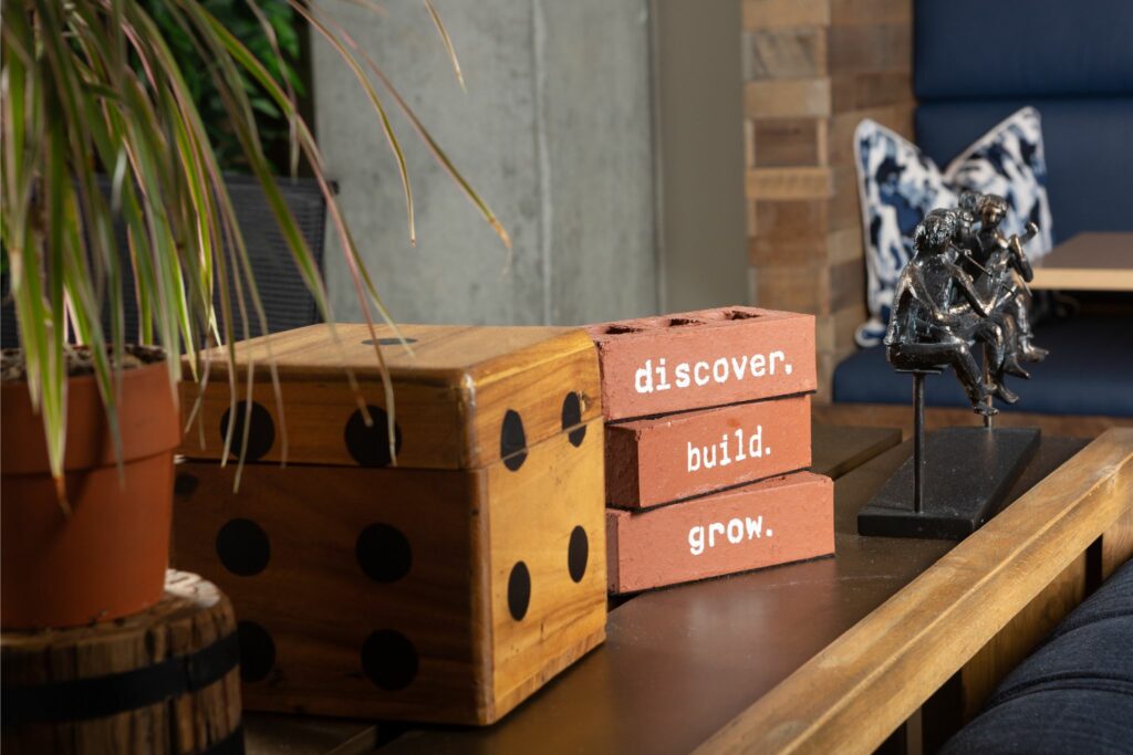 Decorative elements in a coworking space, including dice, a plant, and motivational blocks with the words 'discover, build, grow.